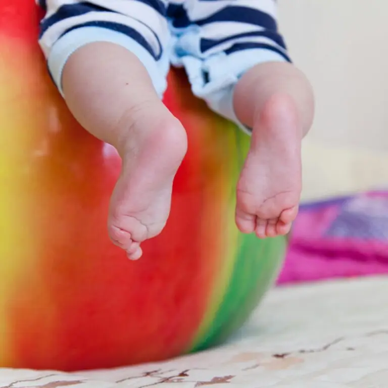 Charming close-up of baby feet on a vibrant exercise ball, capturing a playful moment.
